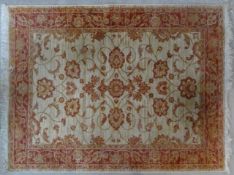 A Ziegler style rug with repeating scrolling floral design across a fawn field within floral