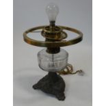 A 19th century oil lamp with clear glass reservoir on cast metal base converted to electricity. H.