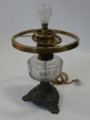 A 19th century oil lamp with clear glass reservoir on cast metal base converted to electricity. H.