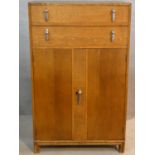 A mid century oak Art Deco style tallboy cabinet with two drawers above panel doors fitted with