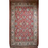 A Persian style flat weave carpet with scrolling leaves on madder ground within floral borders. L.