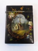 A 19th century paper mache, painted and gilded hinged lidded card case, front has a design with a