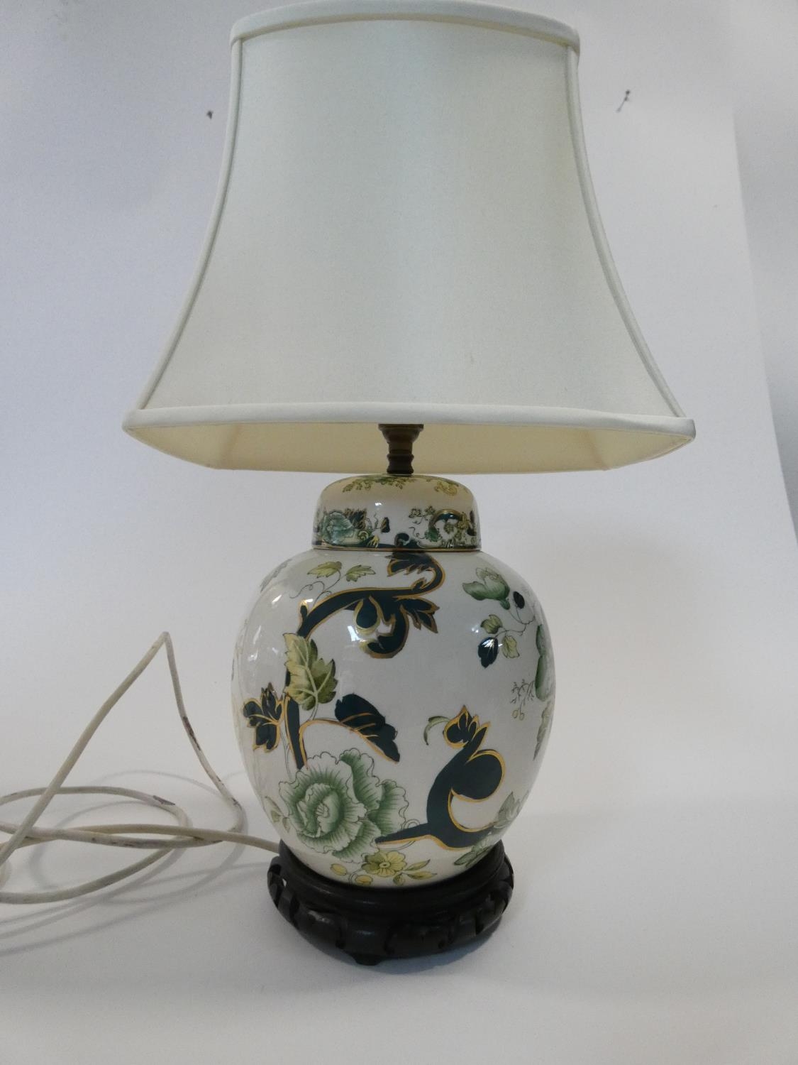 A Chinese style lidded ginger jar converted to a table lamp, mounted in a carved wooden stand.