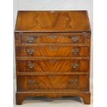 A Georgian style flame mahogany bureau with fitted interior and four long graduating drawers on