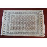 An Eastern woollen rug with repeating lozenge motifs on a beige ground within stylised multiple