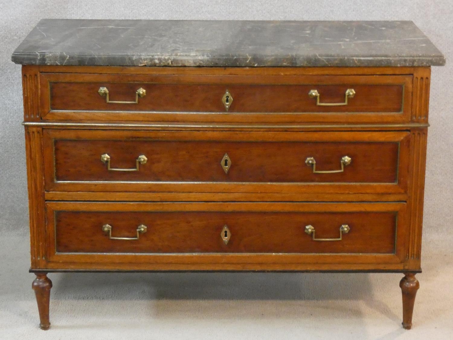 A late 19th century French walnut marble topped commode with three long drawers, brass handles and