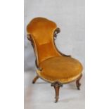A Victorian mahogany framed nursing chair in gold upholstery on carved cabriole supports. H.90cm