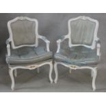 A pair of white painted Louis XV style fauteuils in damask upholstery and fitted squab cushions on