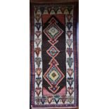A Persian Kilim with repeating lozenge medallion on umber ground contained by plain spandrels and