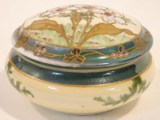 An antique hand painted and gilded porcelain lidded trinket box. The lid decorated with stylised