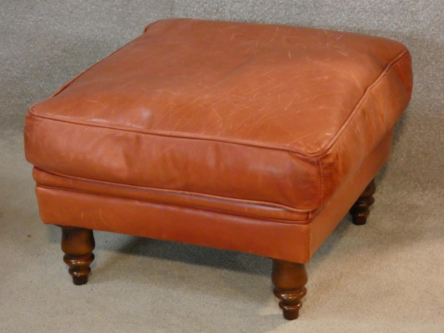 A leather upholstered footstool on turned tapering supports. H.37 W.58 D.58
