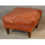 A leather upholstered footstool on turned tapering supports. H.37 W.58 D.58