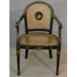 An antique black lacquered and Chinoiserie decorated open armchair with caned back and seat on