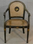 An antique black lacquered and Chinoiserie decorated open armchair with caned back and seat on