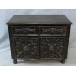 An antique oak side cabinet with carved drawers and doors on circular squat supports. H.73 W.93 D.