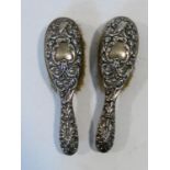 A pair of hallmarked English silver backed brushes with monogrammed cartouches to the embossed