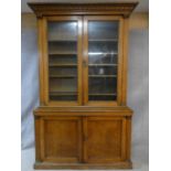 A mid 19th century oak library bookcase with acanthus carved pediment above glazed doors enclosing