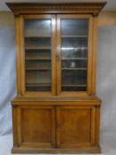 A mid 19th century oak library bookcase with acanthus carved pediment above glazed doors enclosing