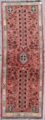 A Persian Shiraz runner with central medallion and trellis design on salmon pink ground within