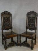 A pair of Continental antique oak hall chairs with crown crestings to the carved backs above panel