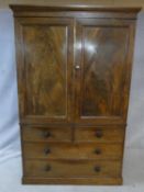 A mid 19th century figured mahogany linen press with panel doors enclosing linen slides above two