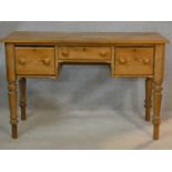 A 19th century pitch pine kneehole writing table with three frieze drawers on turned tapering