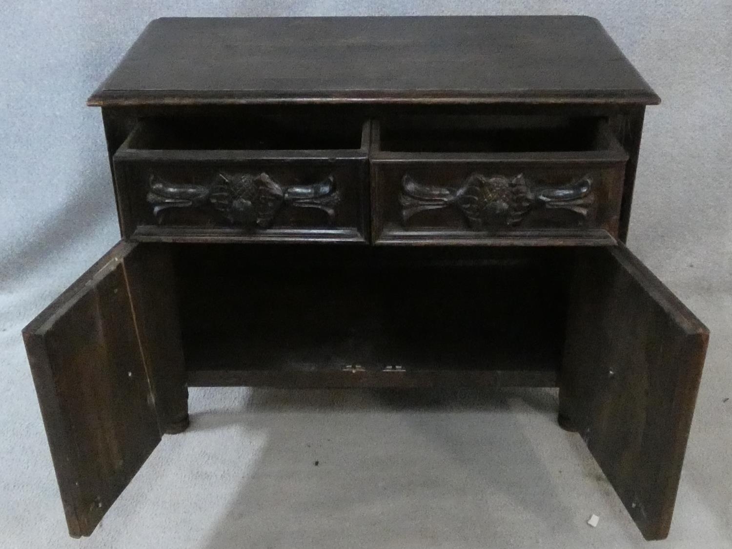 An antique oak side cabinet with carved drawers and doors on circular squat supports. H.73 W.93 D. - Image 2 of 8