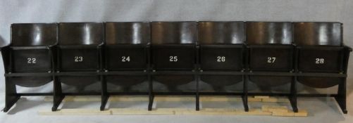 A row of seven vintage theatre seats with laminated plywood backs and seats and painted seat