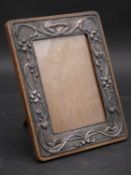 An early 20th century English hallmarked silver cedar backed easel picture frame with embossed Art