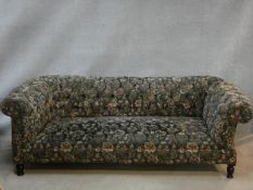 A 19th century drop end Chesterfield sofa in floral buttoned upholstery on turned tapering supports.