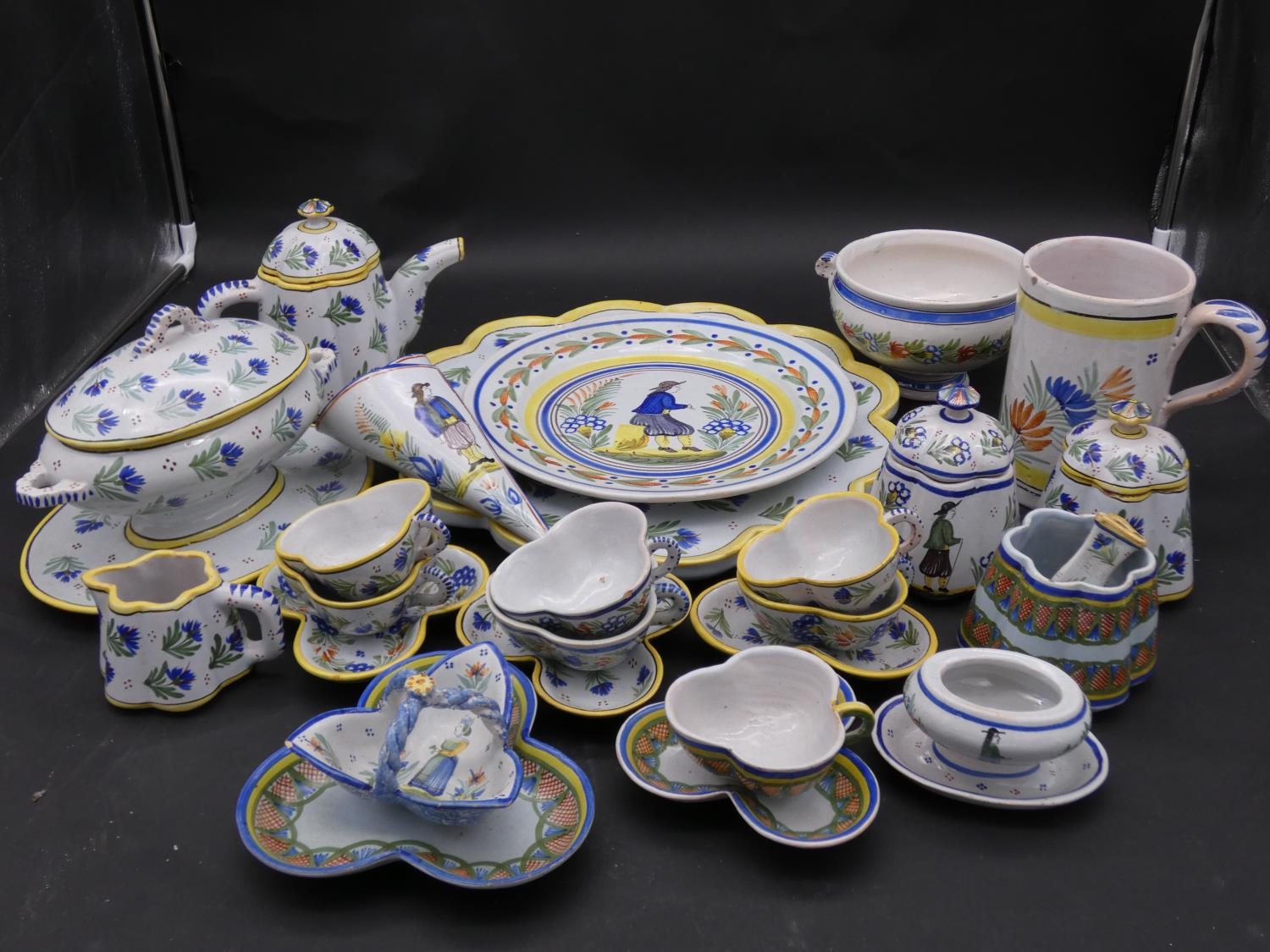 A large collection of antique Adolphe Porquier Quimper hand painted pottery dinner ware. Decorated