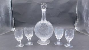 A antique circular etched floral and foliate design crystal decanter with four wine glasses. The