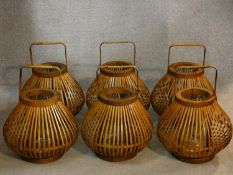 Six Chinese style storm lanterns in caned cases with carrying handles. H.35cm