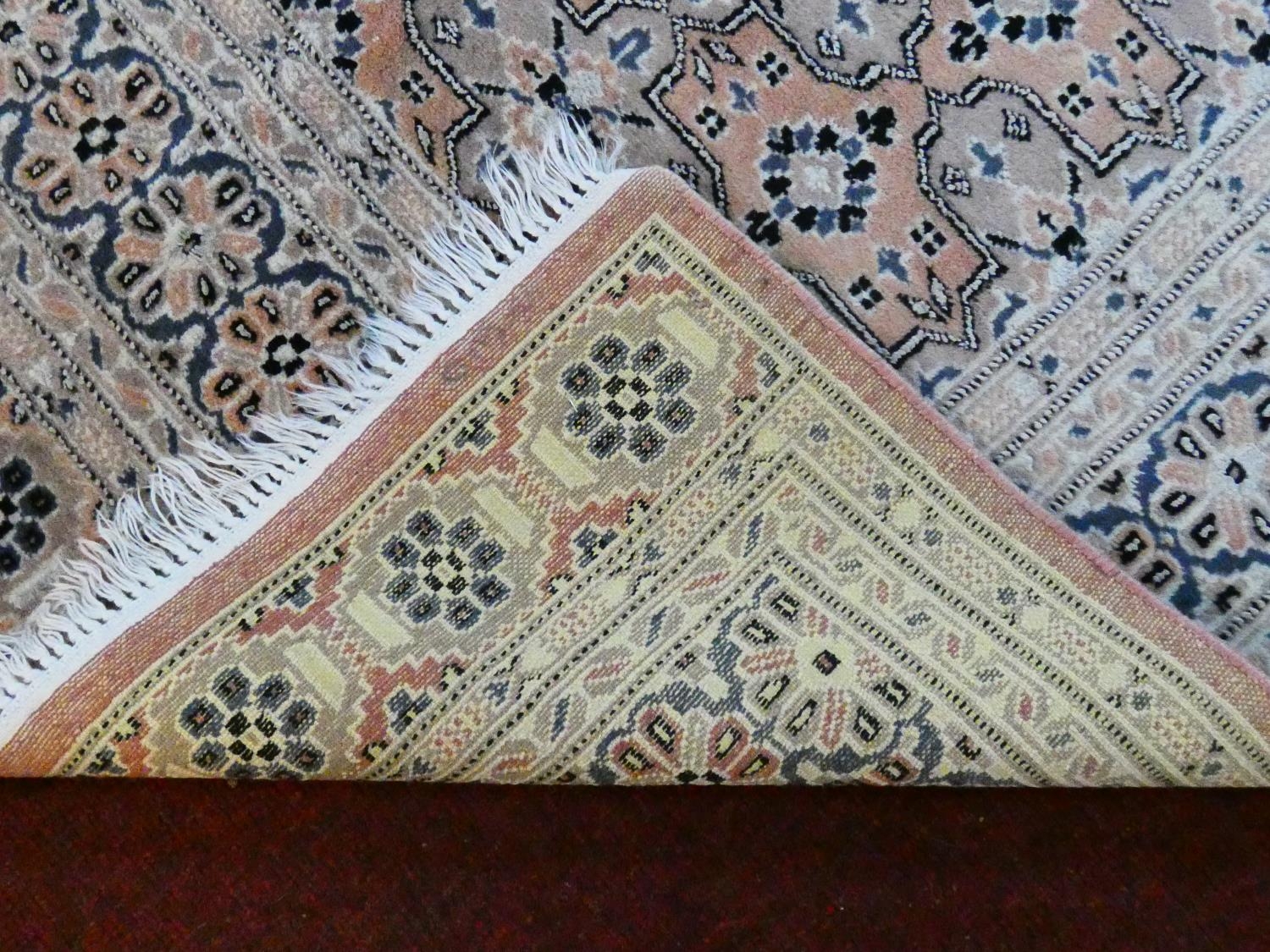 An Eastern woollen rug with repeating lozenge motifs on a beige ground within stylised multiple - Image 4 of 7