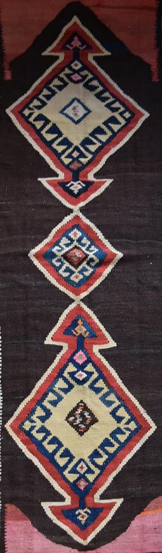 A Persian Kilim with repeating lozenge medallion on umber ground contained by plain spandrels and - Image 2 of 4