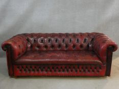 A Chesterfield sofa in buttoned leather upholstery. H.70 L.190 D.90cm (worn in places as