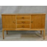 A mid century vintage Gordon Russell teak sideboard with central drawers flanked by cupboards on