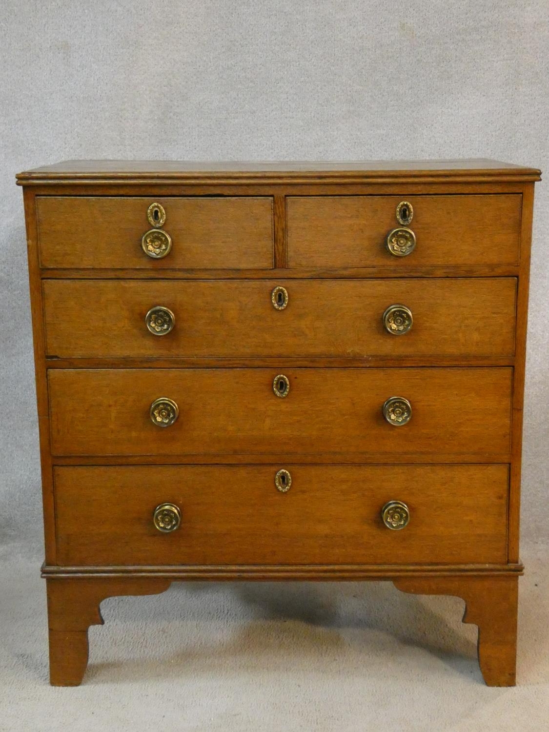 An early 19th century light oak chest of two short over three long drawers fitted with original