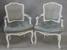 A pair of white painted Louis XV style fauteuils in damask upholstery and fitted squab cushions on