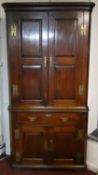 A Georgian oak two section corner cupboard with fielded panel doors enclosing shaped shelves and a