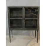 A contemporary vintage industrial style metal display cabinet or bookcase on tapering supports. H.