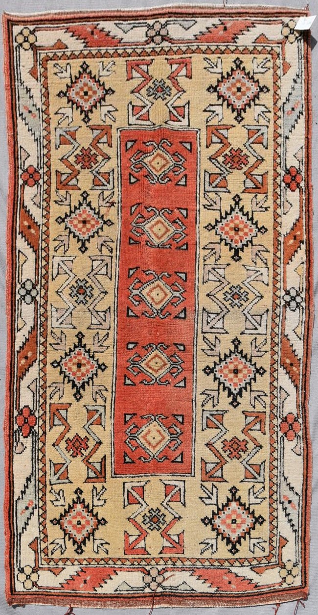 A Turkish Millas rug with repeating central flowerhead motif contained within broad stylised borders