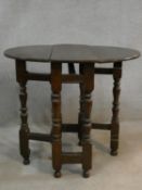 An antique oak drop flap table with gateleg action on turned stretchered supports. (frieze drawer