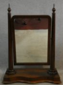 A mid 19th century flame mahogany swing toilet mirror with finials to the mirror supports sitting on