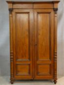 A late 19th century mahogany two section Continental wardrobe with stepped cornice above panel doors