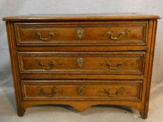 A 19th century French Provincial chestnut commode chest of three long drawers on a shaped apron to