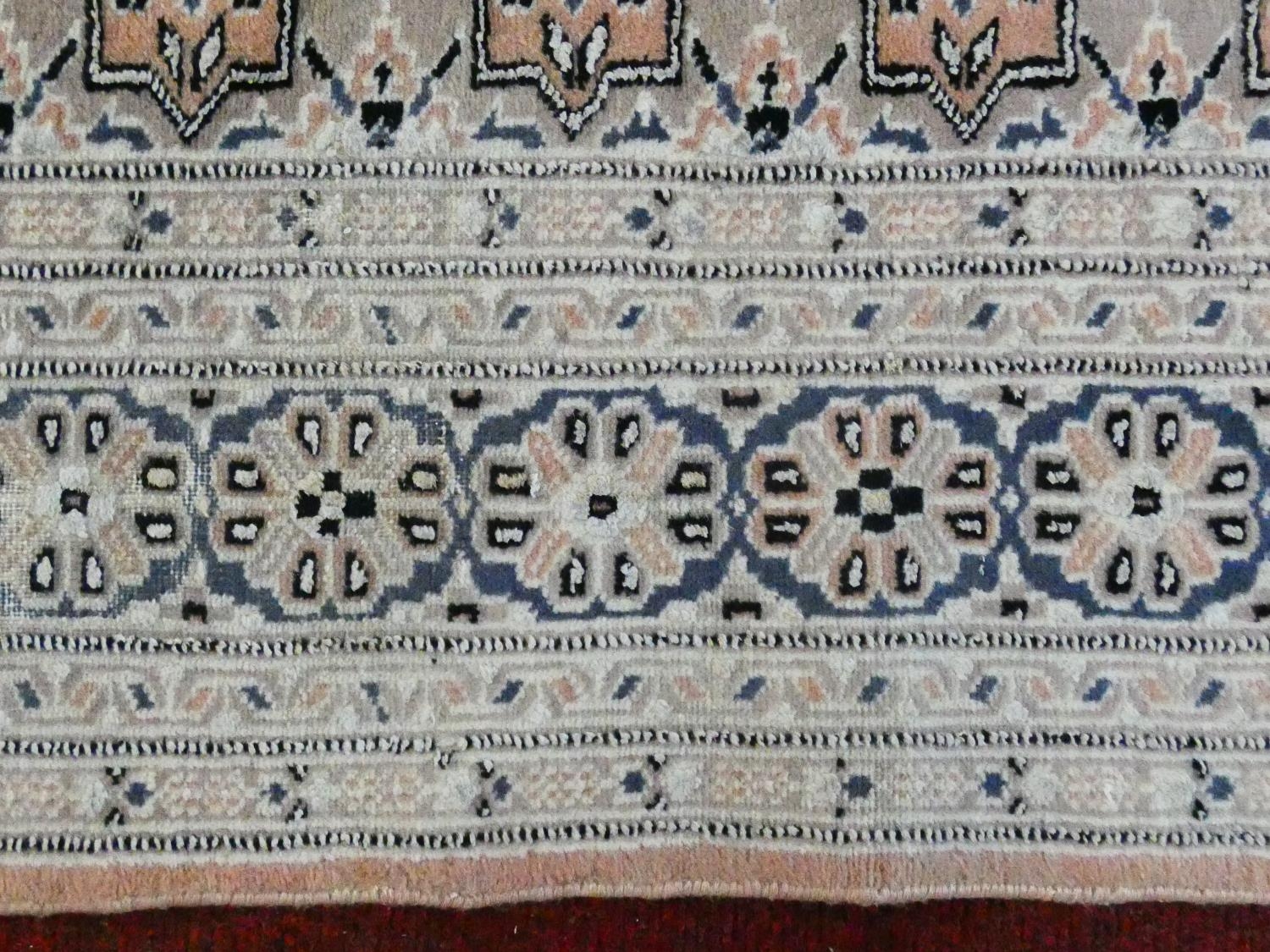 An Eastern woollen rug with repeating lozenge motifs on a beige ground within stylised multiple - Image 6 of 7