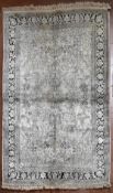 A Kashmir silk rug with all over scrolling floral design contained by foliate multi borders. L.