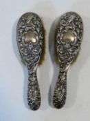 A pair of hallmarked English silver backed brushes with monogrammed cartouches to the embossed