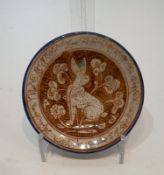 An Islamic glazed ceramic lustre plate decorated with a hare among flowers within a calligraphic